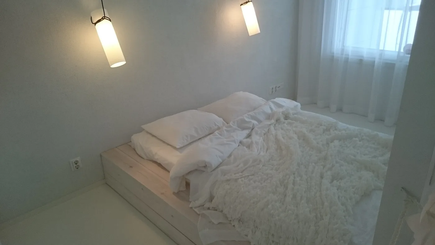 Quarto claro com iluminação junto à cama